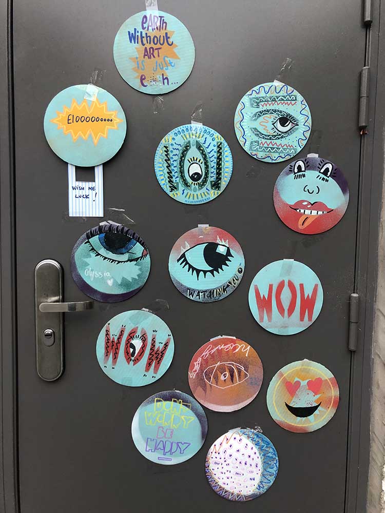 A door full of circular graffiti spray painted boards and drawn with paint pens