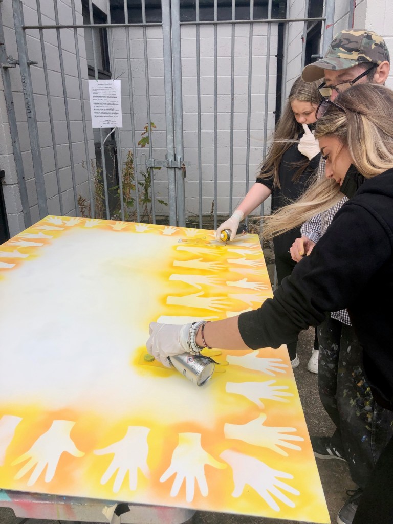 hands spray painted on to community sign