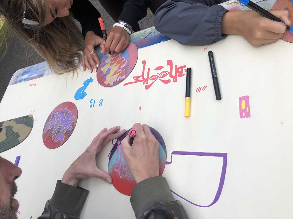 drawing with paint pens on circular graffiti spray painted boards